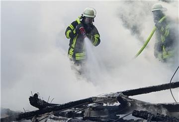 Feuerwehrleute stehen im Qualm und löschen einen Schuppen