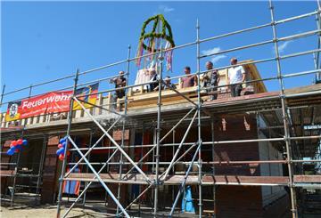 Die Flasche ging beim Richtspruch der Zimmerer für das neue Schiffdorfer Feuerwehrhaus zu Bruch, die Scherben sollen dem Bau traditionell Glück bringen.