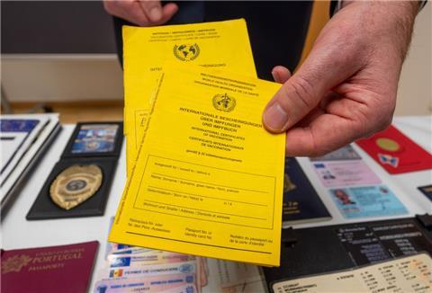 Ein Polizist zeigt am Rande der Jahresbilanz 2021 der bayerischen Grenzpolizei gefälschte Impfpässe. 