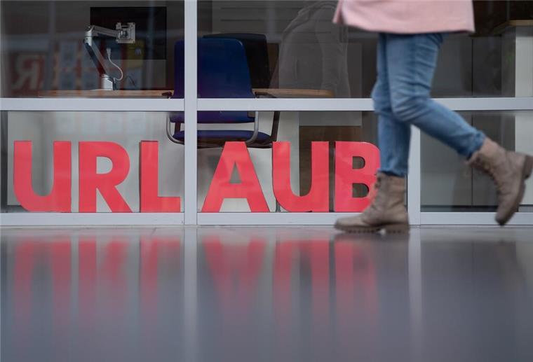 Ein Mensch geht zu Fuß vor einem »Urlaubs-Schriftzug«.