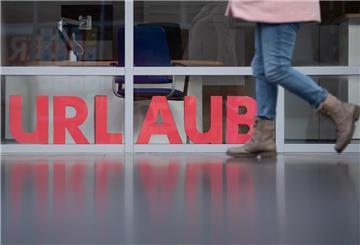 Ein Mensch geht zu Fuß vor einem »Urlaubs-Schriftzug«.