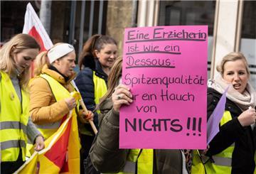 Eine Demonstrantin trägt bei einem Protestmarsch durch die Friedberger Innenstadt ein Plakat und der Aufschrift "Eine Erzieherin ist wie ein Dessous: Spitzenqualität für einen Hauch von Nichts"".