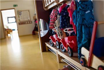 Bobbycars stehen unter Jacken von Kindern, die an einer Garderobe einer Kindertagesstätte (Kita) hängen