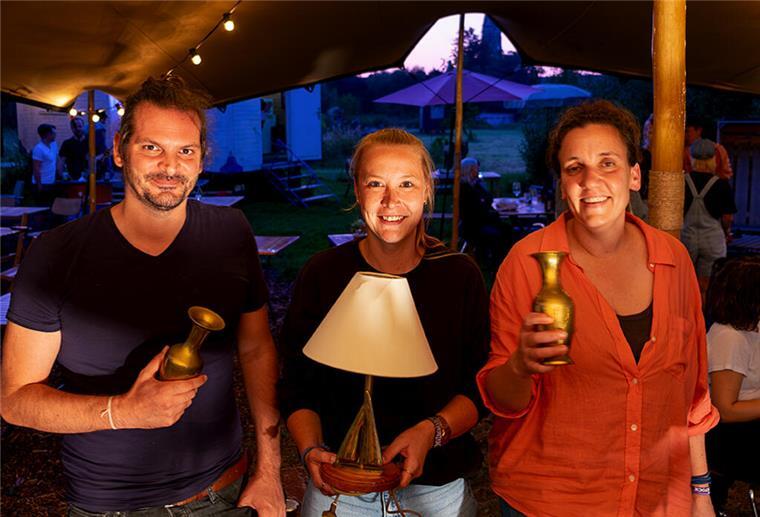 Ein Mann und zwei Frauen halten Preise hoch