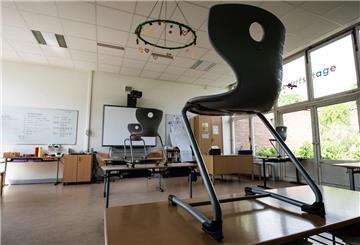 Mehrere Stühle stehen in einem Klassenzimmer auf den Tischen.