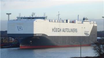 Ein großes Autotransportschiff der Reederei Höegh Autoliners mit dem Namen „Höegh Sunlight“ in einem Hafen. Das Schiff ist weiß und grau lackiert und trägt die Aufschrift „LNG Powered“.