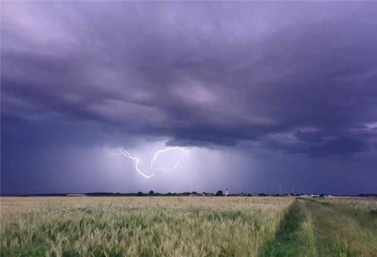  Dunkle Gewitterwolken und Blitz über Feld