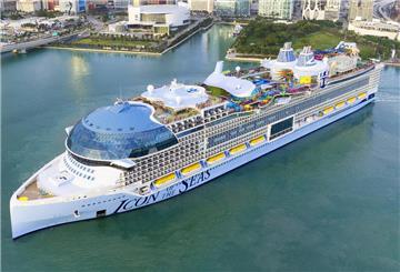 Die Icon of the Seas liegt im Wasser vor einer Großstadt. Sie ist das größte Kreuzfahrtschiff der Welt.