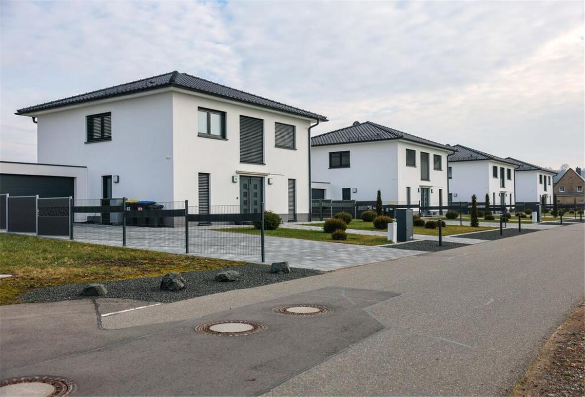Immobilien werden deutlich teurer: So heftig ist der Preisanstieg wirklich Vier uniforme Einfamilienhäuser stehen neu erbaut an einer Straße.