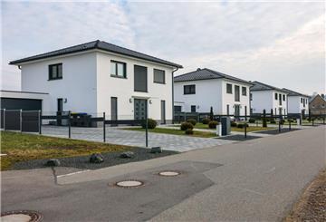 Vier uniforme Einfamilienhäuser stehen neu erbaut an einer Straße.