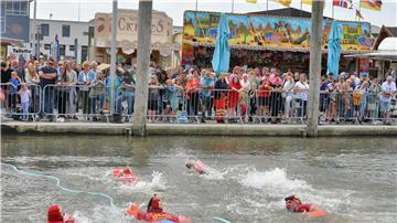 Menschen schwimmen vor Publikum im Wasser.