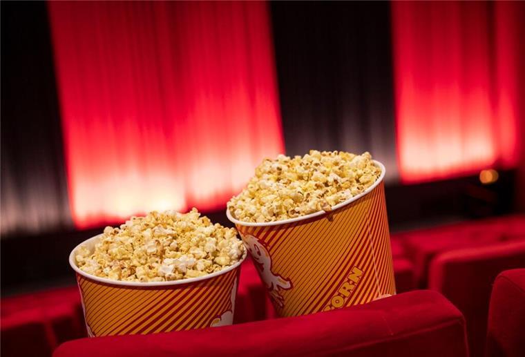 Popcorn steht zwischen den Sitzreihen in einem Kino.