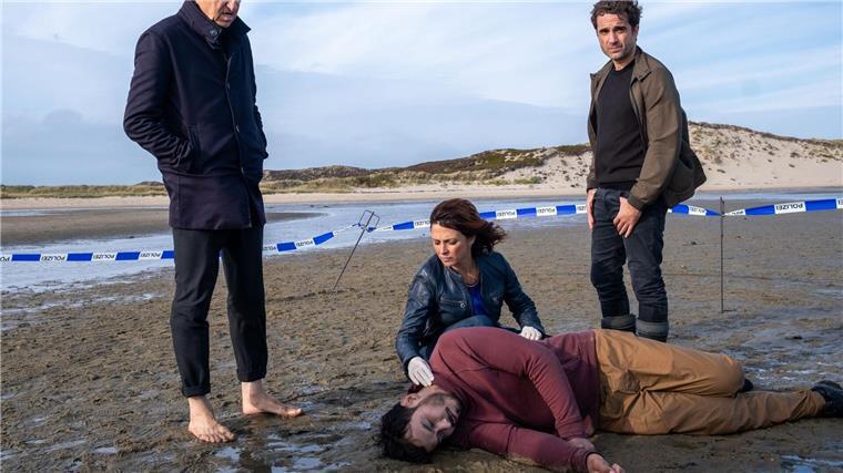 Die Kommissare Carl Sievers (Peter Heinrich Brix, l.), Ina Behrendsen (Julia Brendler) und Hinnerk Feldmann (Oliver Wnuk, r.) mit dem Toten im Watt.