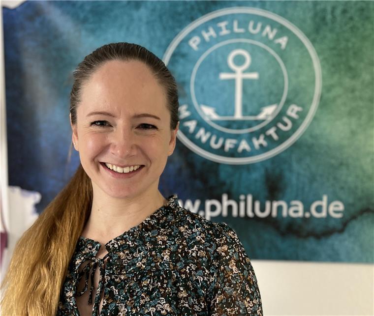 Eine Frau mit langen blonden Haaren im Zopf lächelt in die Kamera. 