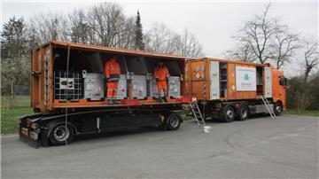 Das Foto zeigt das orangefarbene Schadstoffmobil des Landkreises Cuxhaven. Zwei Männer stehen in dem Mobil. 