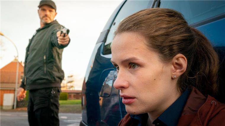Die Kronzeugin Fiona (Marlene Tanczik) wird von einem Söldner (Christoph Domanski) mit einer Waffe bedroht.