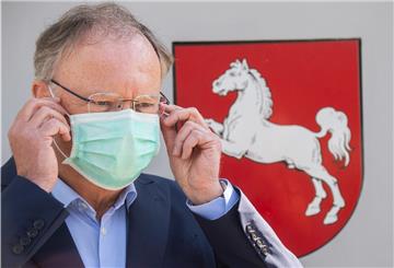 Stephan Weil (SPD), Ministerpräsident Niedersachsen, steht vor der Staatskanzlei und zieht einen Mundschutz an. 