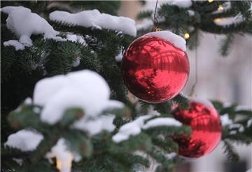 Eine schneebedeckte Kugel hängt an einem Weihnachtsbaum. 