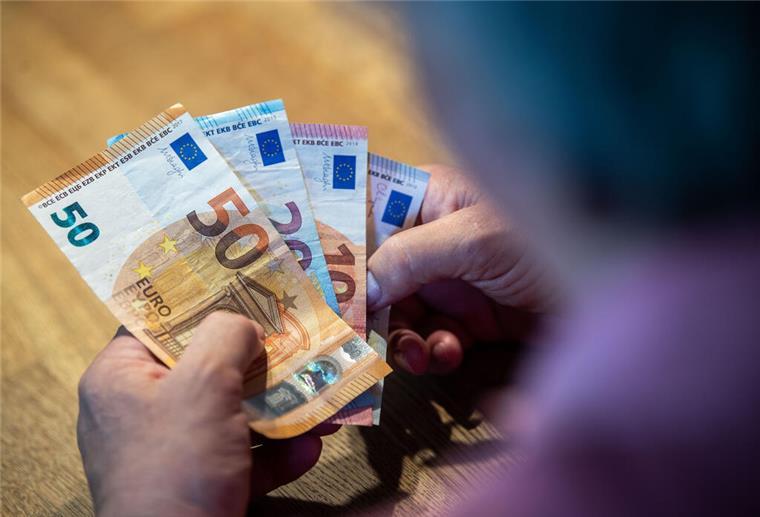 Ein älterer Mann sitzt an einem Tisch und zählt Geld.