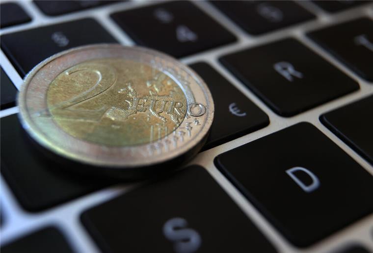  Eine Zwei -Euro-Münze liegt auf der Tastatur eines Laptops neben einem Eurozeichen. 