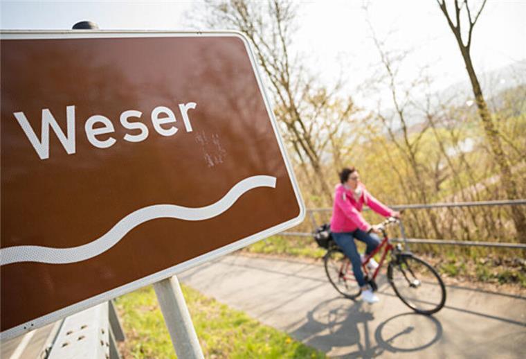 Radfahrerin fährt auf Weser-Radweg