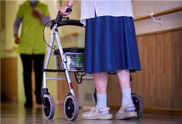 Eine ältere Dame geht mit ihrem Rollator über einen Flur.