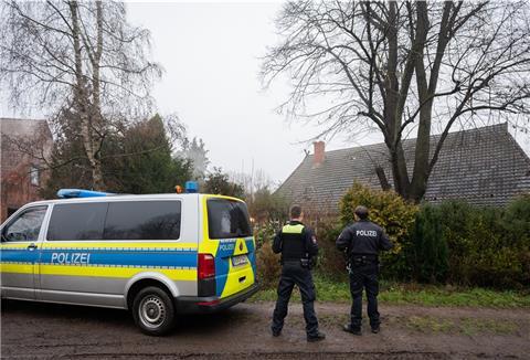 Zwei Polizisten stehen vor einem Haus in Fischerhude