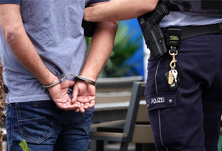 Cuxhaven: Zwei Männer nach Diskostreit lebensgefährlich verletzt Ein Mann steht in Handschellen neben einem Polizisten.