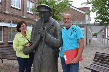 Die Nachtwächter-Skulptur am Eingang zum Lindenhof macht deutlich, dass der Innenbereich des Geschäftszentrums Mittelpunkt sein wird beim großen Ortsgemeinschaftsfest in Langen. Darauf freuen sich: Alice Roes, Teamleiterin der Stadt für den Bereich Tourismus und Kultur, und Jörn Wiebke, Organisator bei der Werbegemeinschaft Langen.