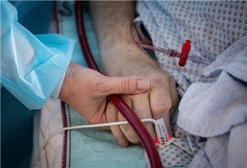 Eine Krankenschwester versorgt einen schwer an Corona erkrankten Patienten auf der Intensivstation des Klinikums in Fulda und hält dabei die Hand des Mannes. 