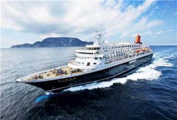 Ein Kreuzfahrtschiff auf dem Meer. Im Hintergrund ist ein Berg zu sehen. 
