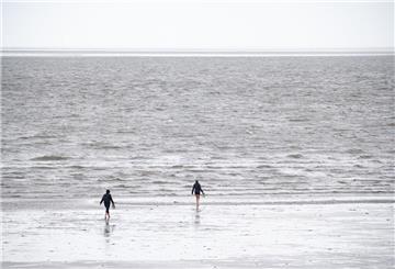 ARCHIV - 30.07.2023, Schleswig-Holstein, Büsum: Spaziergänger sind im Watt vor Büsum unterwegs. (zu dpa: «Bundesamt: Nord- und Ostsee 2024 überdurchschnittlich warm») Foto: Jonas Walzberg/dpa +++ dpa-Bildfunk +++