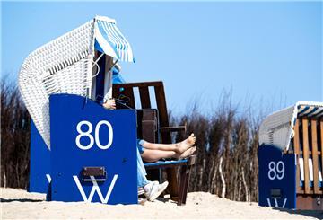 Menschen sitzen in einem Strandkorb am Strand.