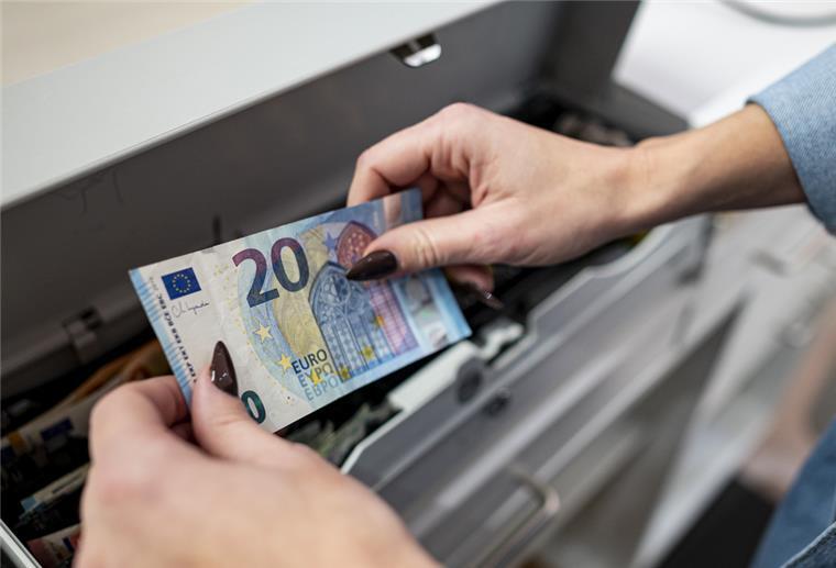 Eine Mitarbeiterin legt Geld in die Kasse 