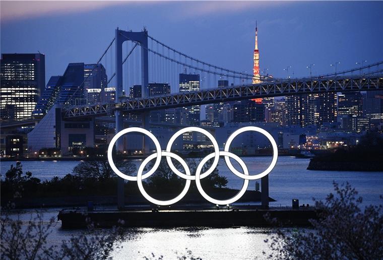 Verschiebung von Olympia offenbar beschlossen Die Olympischen Ringe stehen im Hafenviertel Daiba in Tokio vor der Regenbogenbrücke und dem Tokio-Turm beleuchtet.