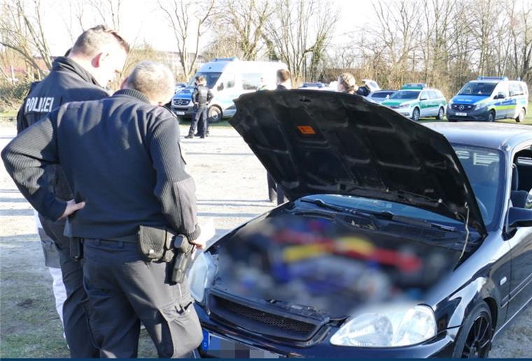 Zwei Polizisten stehen vor einer geöffneten Motorhaube.