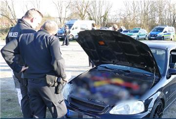 Zwei Polizisten stehen vor einer geöffneten Motorhaube.