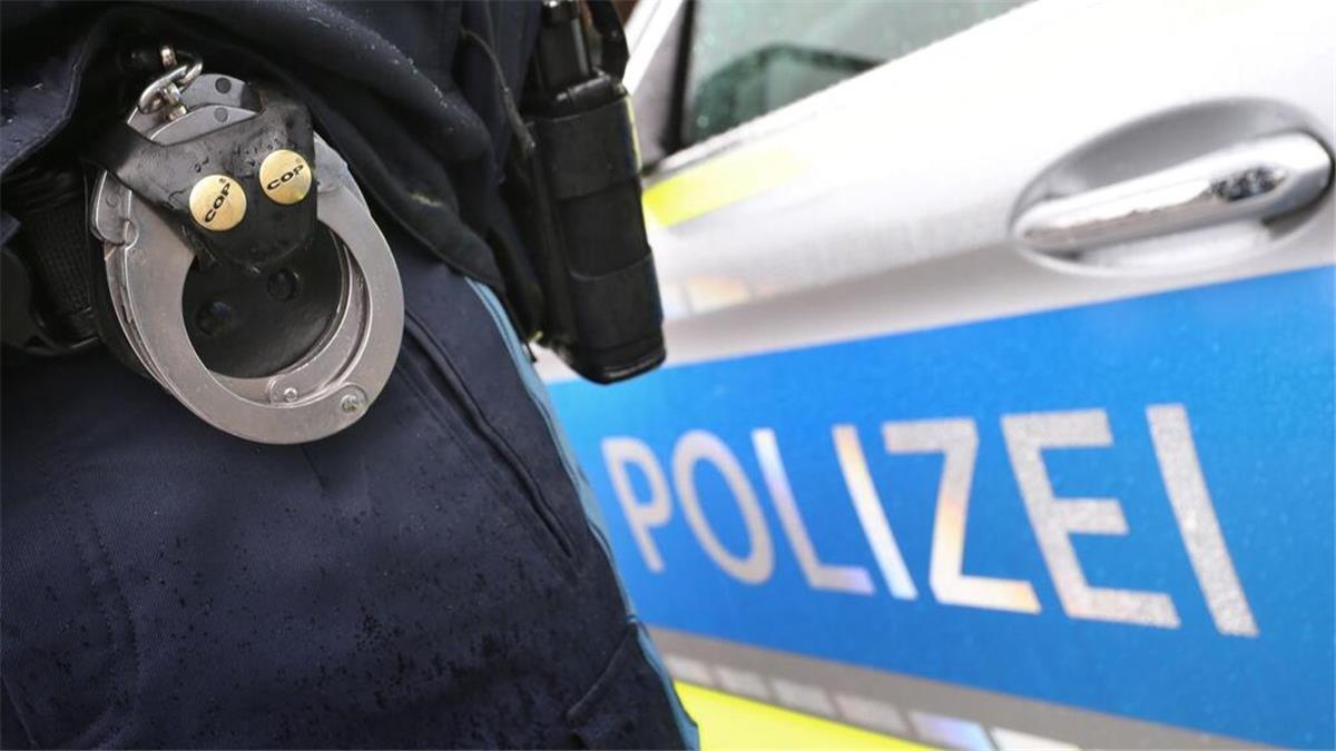 Beziehungsstreit: Frau (32) nach Messerattacke in Lehe festgenommen Ein Polizist mit Handschellen und einer Pistole am Gürtel steht vor einem Streifenwagen.