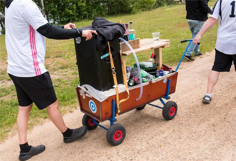 Teilnehmer einer Vatertagstour ziehen am mit einem Bollerwagen umher