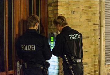 Zwei Polizisten klingeln  (Niedersachsen) an einer Haustür.