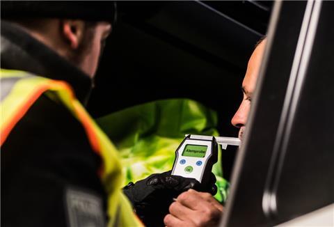 Ein Polizist kontrolliert einen LKW-Fahrer auf Alkoholgenuss. 
