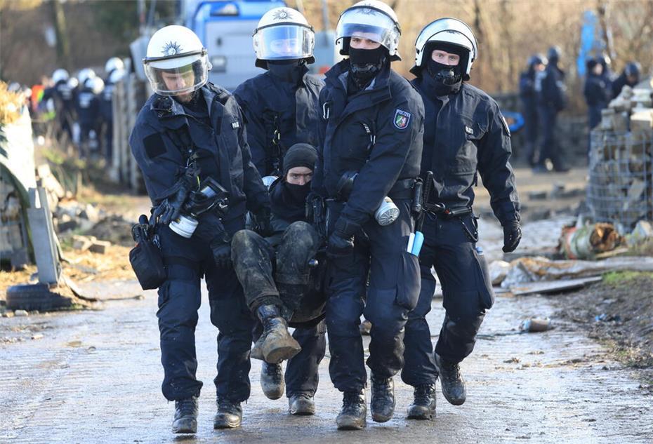 Polizisten tragen einen Klimaaktivisten vom besetzten Braunkohleort Lützerath weg.