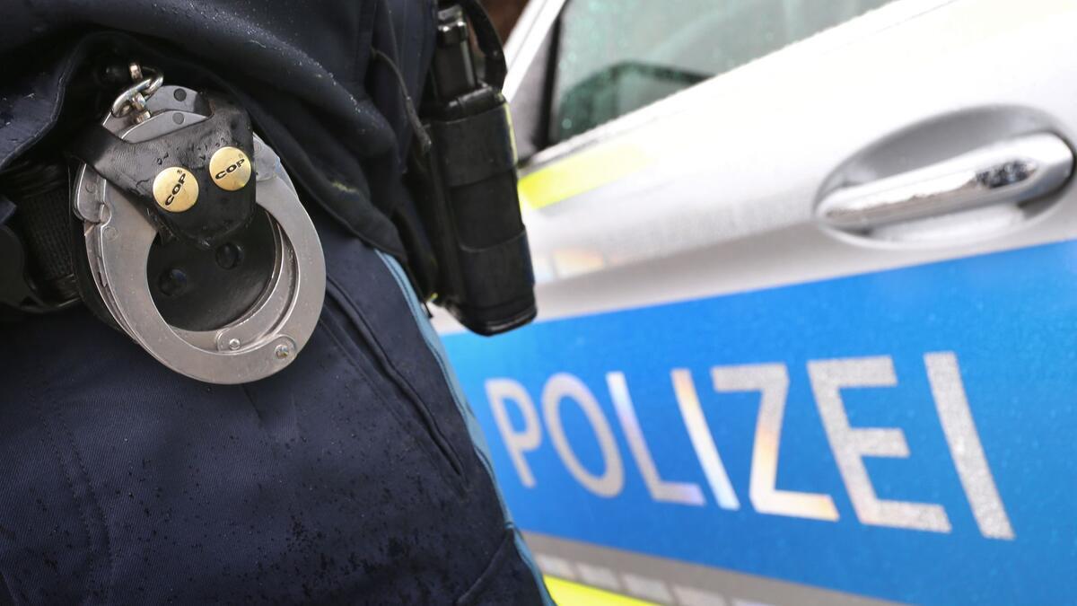 Polizei ermittelt - Lkw-Fahrer bedroht Frau nach Unfall in Bremerhaven Ein Polizist mit Handschellen und einer Pistole am Gürtel steht vor einem Streifenwagen.