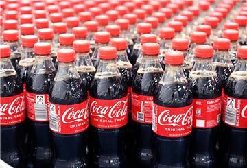 Coca Cola Flaschen stehen auf einem Förderband.