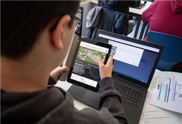 Schülerinnen und Schüler nehmen im Klassenzimmer am Unterricht mit Hilfe von Laptops und Tablets teil.