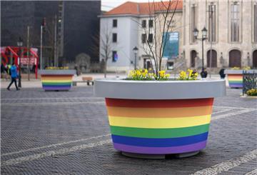Ein Kübel in regenbogenfarben ist auf einem öffentlichen Platz zu sehen.