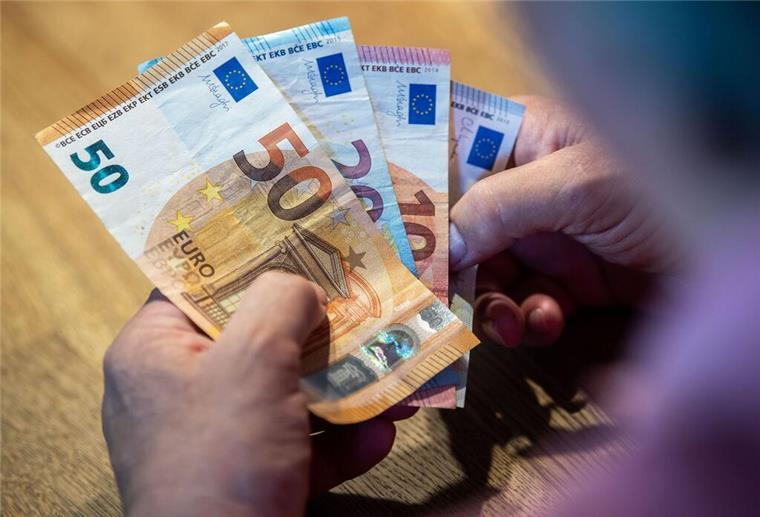 Ein älterer Mann sitzt an einem Tisch und zählt Geld.