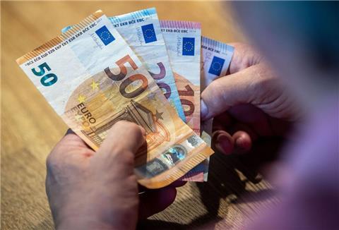 Ein älterer Mann sitzt an einem Tisch und zählt Geld.