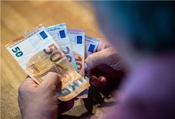 Ein älterer Mann sitzt an einem Tisch und zählt Geld.