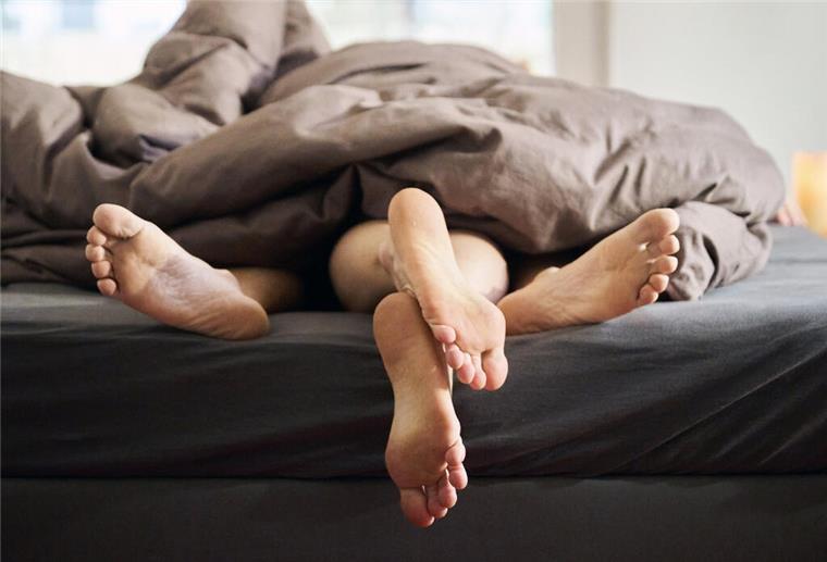 Seltene Allergie: Grippesymptome nach jedem Orgasmus Eine Frau und ein Mann liegen eng umschlungen in einem Bett (gestellte Szene).